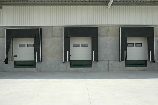 The loading area of a industrial warehouse with several loading bays where truck stop to unlock cargo.