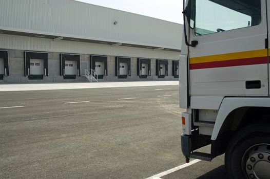 The loading area of a industrial warehouse with several loading bays and a truck.