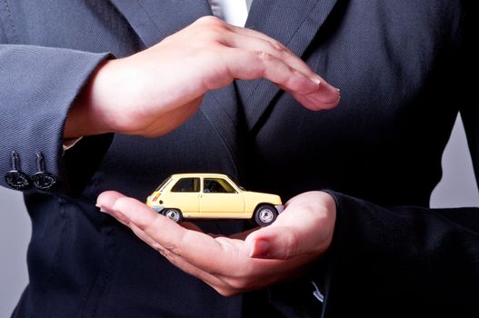 Two hands facing each other, protect a yellow car.