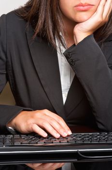 Bored businesswoman sitting at a table and typing on a keyboard