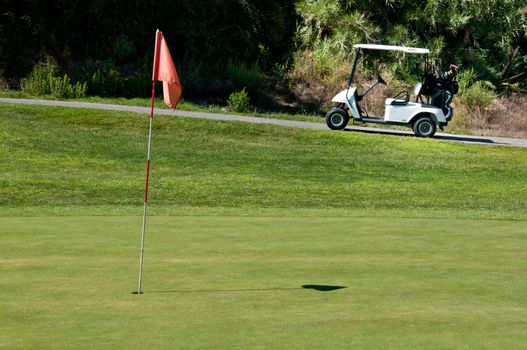 Golf cart next to a hole on a golf course