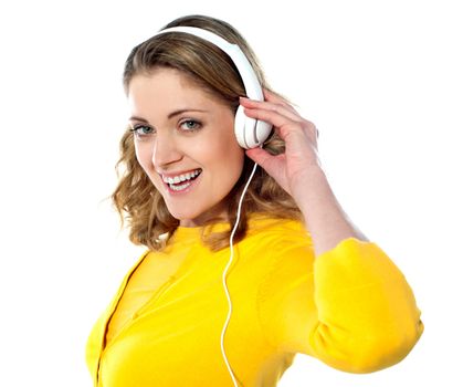 Beautiful young woman with headphones listening music isolated on white background