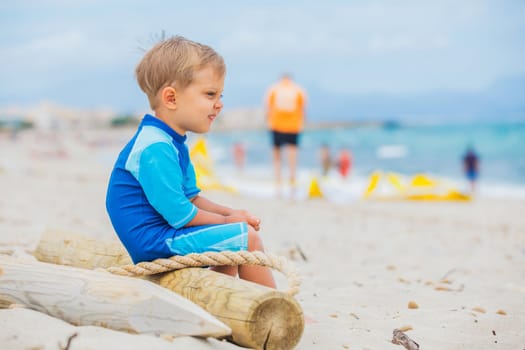 Cute 2 years old boy looking at kiting on tropical beach