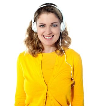 Smiling young woman listening music in headphones. Isolated on white