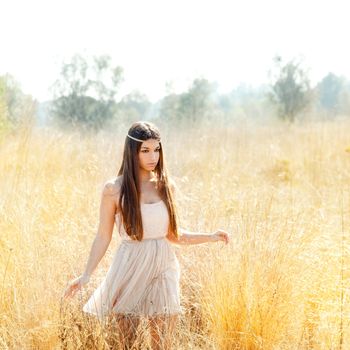 Asian indian woman walking in golden dried grass field