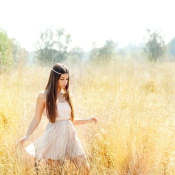 Asian indian woman walking in golden dried grass field