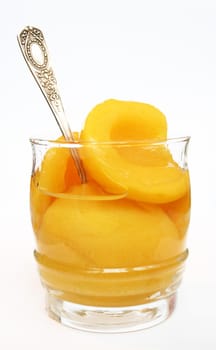 Halves of peaches in a sweet syrup in a glass isolated on the white