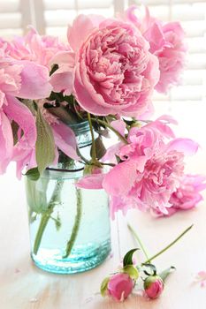 Pink peonies in glass jar on table