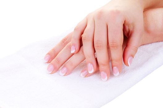 Female hands with nice french manicure on white towel isolated on white background