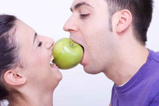 young couple with a green apple between their lips