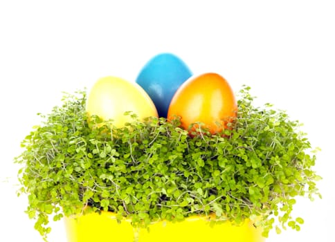 Three different coloured eastrn eggs in a yellow cup