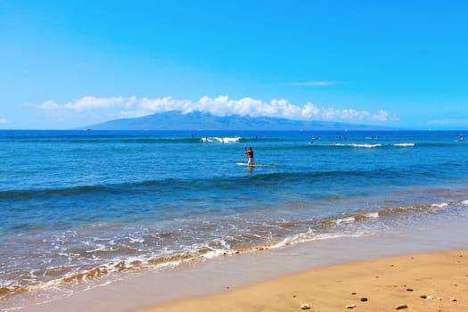 Tropical beach with blue water and surfers.