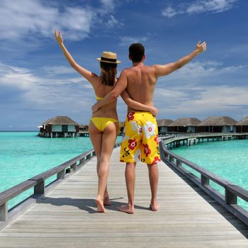 Couple on a tropical beach jetty at Maldives