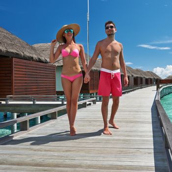 Couple on a tropical beach jetty at Maldives