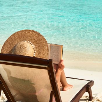 Young woman reading a book at the beach