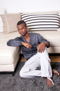 dark-skinned man sitting on the floor in front of the couch