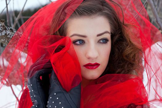 Beautiful woman with dark hair and red lips in white snow