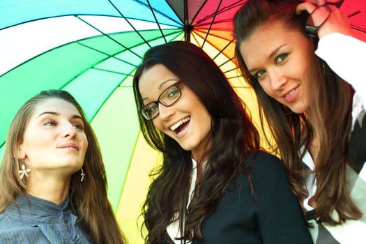 happy smiling girlfriends stay under colourful umbrella  