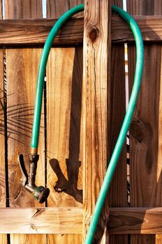 Wood fence and garden hose with spray nozzle.