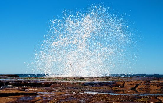 big splash as a wave hits the rocks at the coast