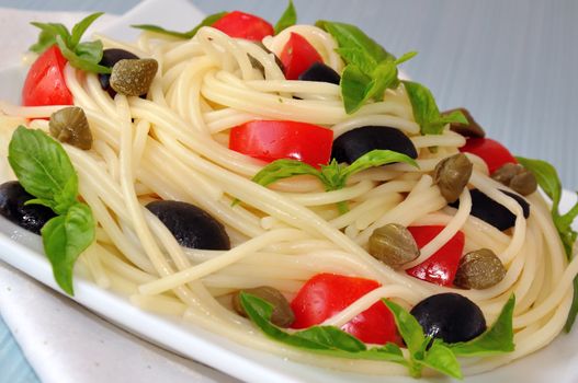 Spaghetti with tomato slices and olives, capers and basil