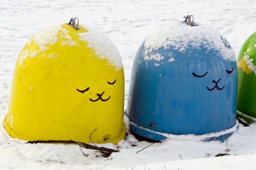 Snow cover plastic bins for sorting waste. Yellow blue and green with drawing in winter.