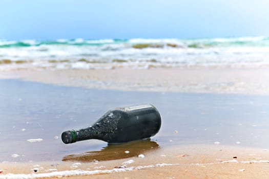 bottle with a note on the sea shore in the background