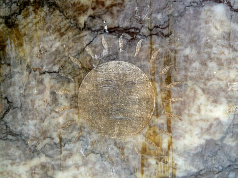 sun face etched on a stone surface