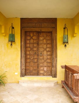 Antique Moroccan style wooden door on yellow wall