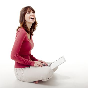 Beautiful woman sitting on the floor laughing  and working with a laptop