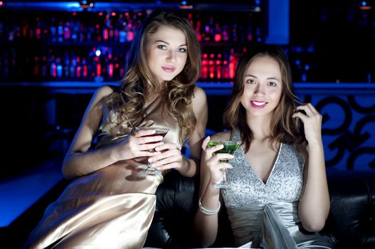 Young beautiful women, have a rest on a sofa and drink beverages