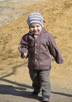 boy is dressed in warm clothes walking on playground