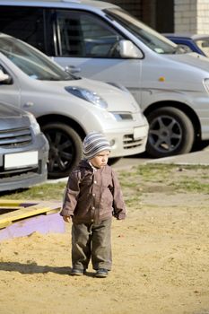 boy is dressed in warm clothes stands on playground