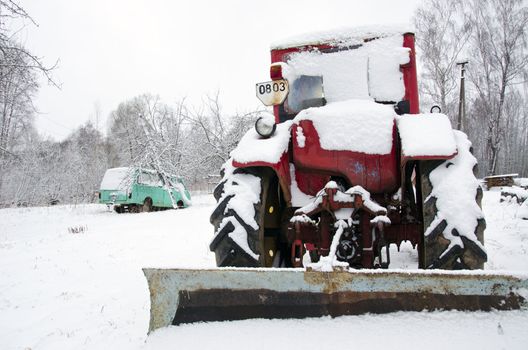 old russian soviet tractor covered with snow in winter. retro vintage machinery adapted to snow plowing.