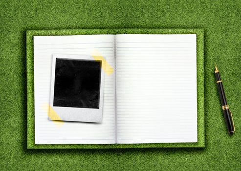 Biography,curriculum vitae concept, blank opened book and empty photo on the green grassland and pen