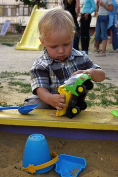baby boy playing with toy auto in sand box