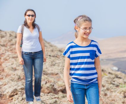 Cute girl and her mother hiking in the cross-country