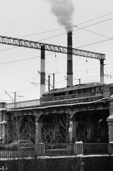 Retro-styled industrial landmark with pipes, smoke, railroad bridge and train
