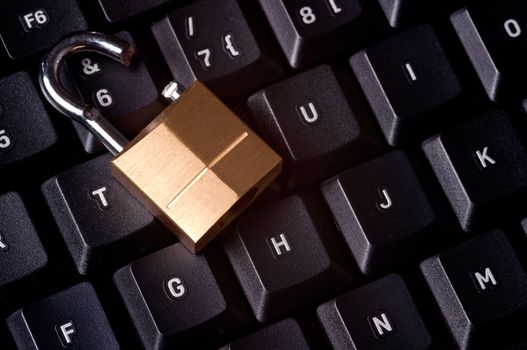 A broken padlock on top a computer keyboard to represent the concept of computer security breach
