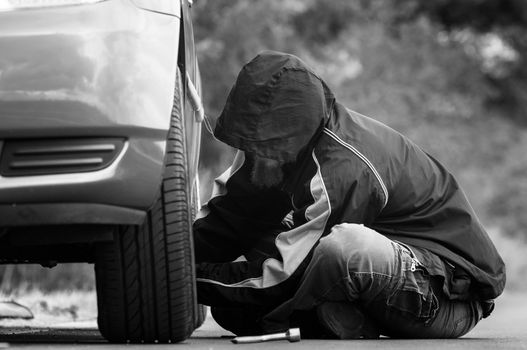 Young adult inspecting the wheel of a car