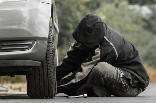 Young man repairing car outdoors sitting