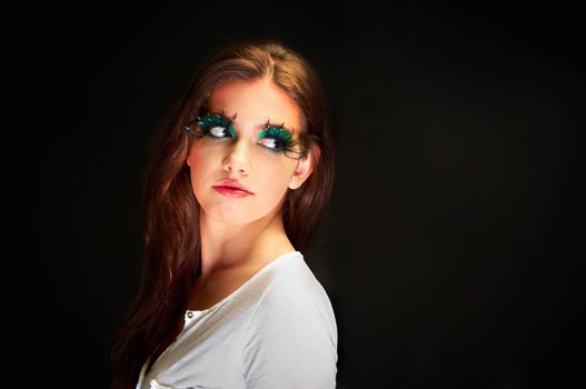 Young wiman in the studio with extreme makeup against dark background