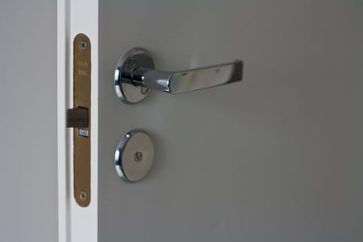 Shining door handle on a white wooden door.