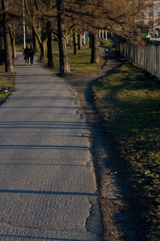 Park road going near a railroad with two people walking