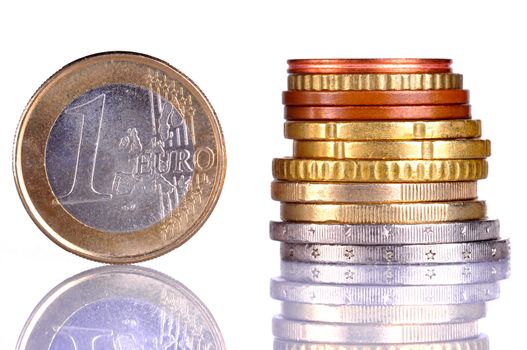 Close up of the oen Euro coin, next to a pile of coins