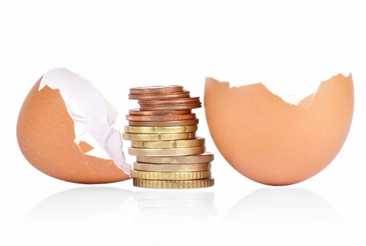 Broken egg shell with coins between on a white background with a shadow underneath