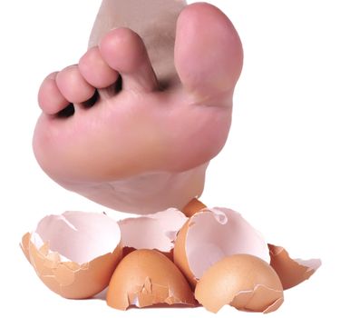 Bare foot about to step on eggshells to illustrate the concept of trying very hard not to upset someone or something