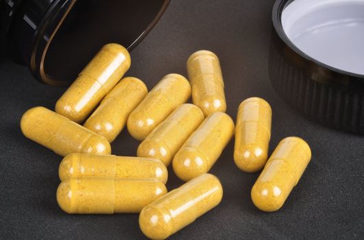 Closeup of a yellow pills coming out of a medicine bottle 