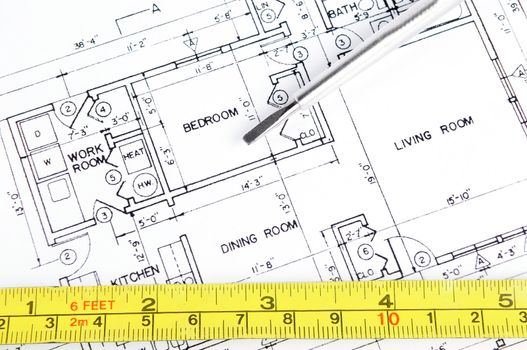 House blueprint with a measuring tape and a screwdriver on top of it