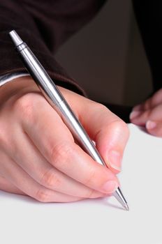 A hand, holding a pen, is ready to write on a document
